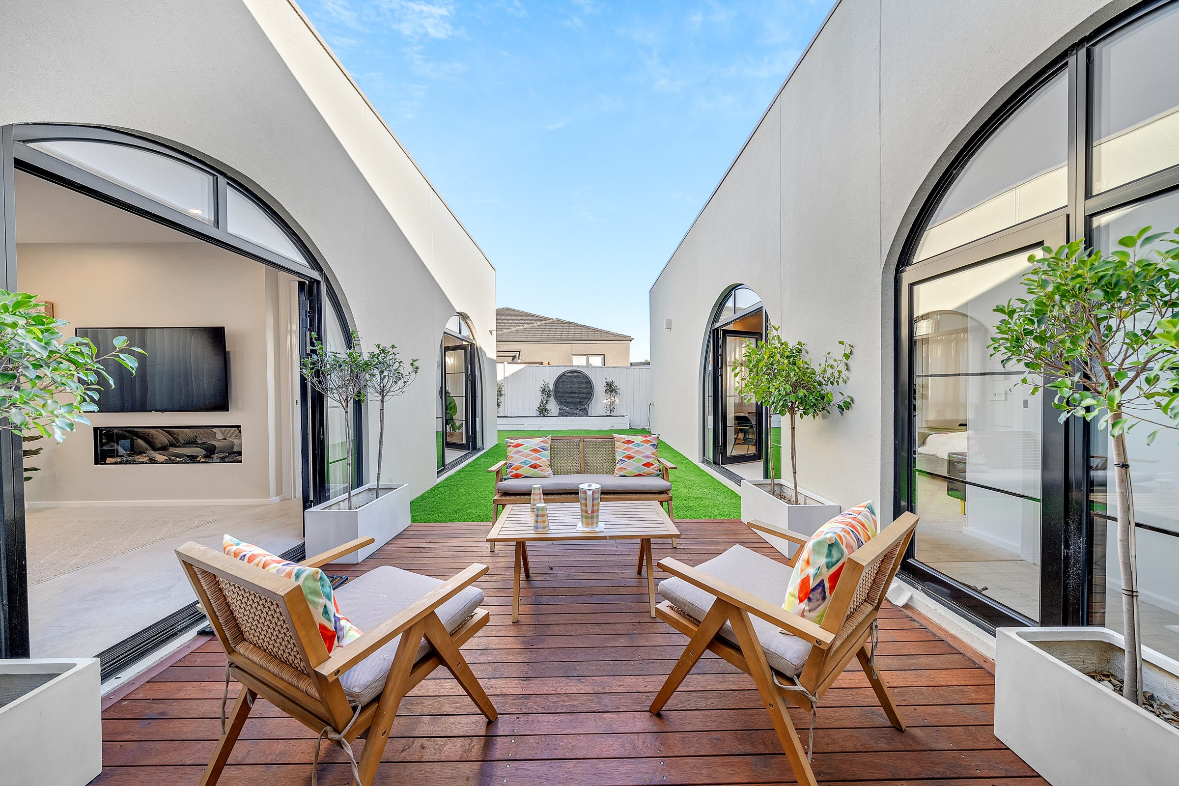 Vanatara Homes courtyard with arched glazing, timber deck and lush garden